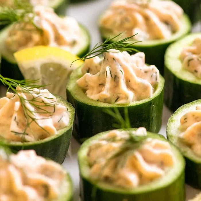 Cucumber cups filled with a creamy filling and garnished with dill and lemon wedges.