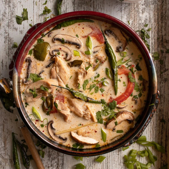 Creamy chicken dish with vegetables in a pan on a wooden surface
