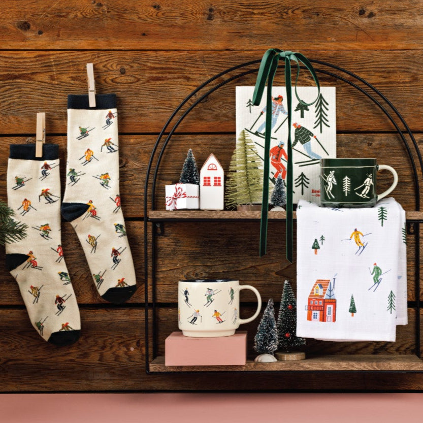Collection of Christmas-themed kitchenware including mugs, a towel, and decorative items on a wooden shelf.