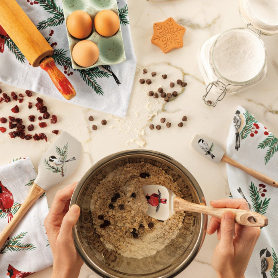 Person mixing ingredients in a bowl with baking tools and ingredients on a marble surface