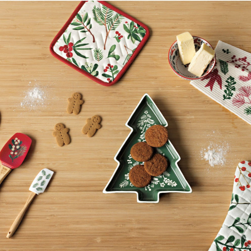 Set of Christmas-themed kitchen items including spatulas, cookie cutters, and oven mitts on a wooden surface.