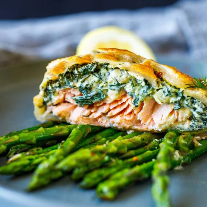Salmon roulade with spinach on a bed of asparagus on a plate.