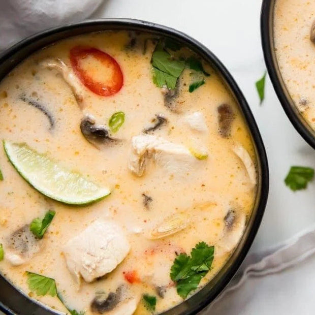 Two bowls of creamy soup with vegetables on a white surface